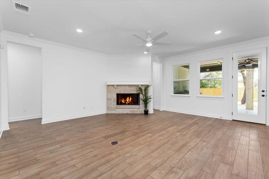 Unfurnished living room featuring a ceiling fan, ornamental molding, wood finished floors, a tiled fireplace, and baseboards Unfurnished living room featuring a ceiling fan, ornamental molding, wood finished floors, a tiled fireplace, and baseboards