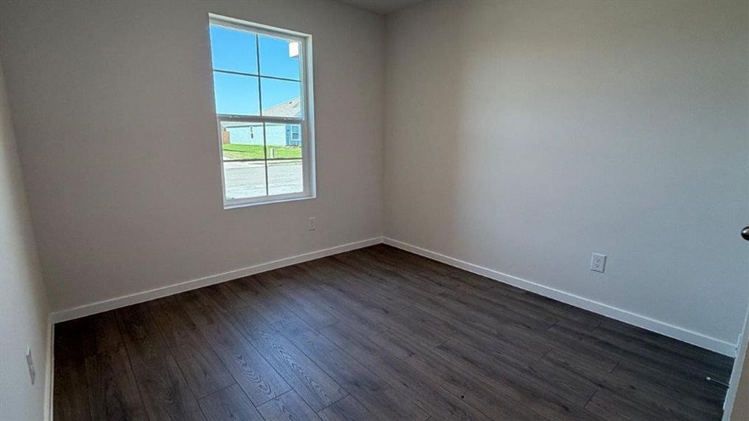 Room featuring a single-pane window with white trim, wood-finish flooring, and light-toned walls Room featuring a single-pane window with white trim, wood-finish flooring, and light-toned walls