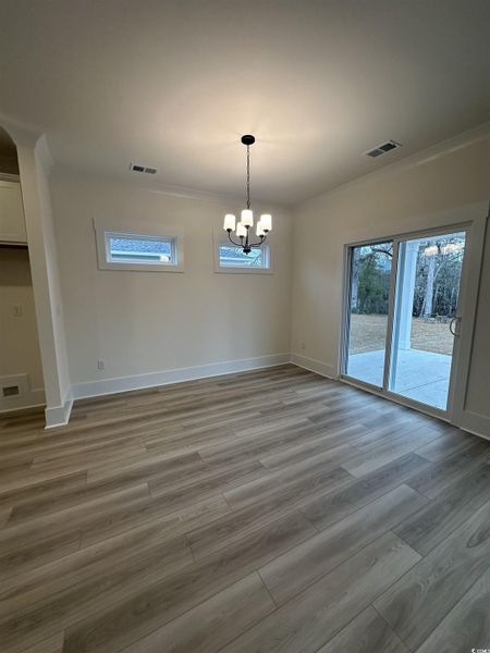 Unfurnished dining area with a chandelier, light wood-style floors, and crown molding