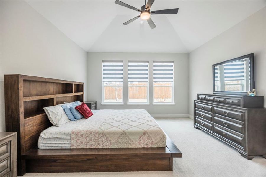 Carpeted bedroom featuring vaulted ceiling, a ceiling fan, and baseboards