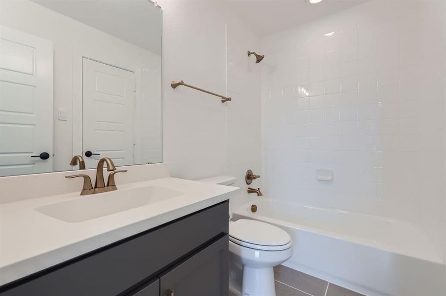 Full bathroom with toilet, tiled shower / bath, vanity, and tile patterned flooring