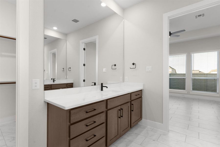Bathroom with vanity, a spacious closet, light marble finish flooring, and recessed lighting
