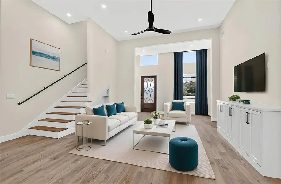 Living room featuring light wood finished floors, recessed lighting, a ceiling fan, and stairs