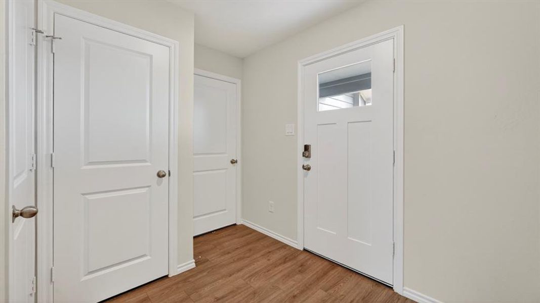 Entryway featuring a Craftsman-style door with upper lite, wood-finish flooring, white baseboards, and neutral wall paint