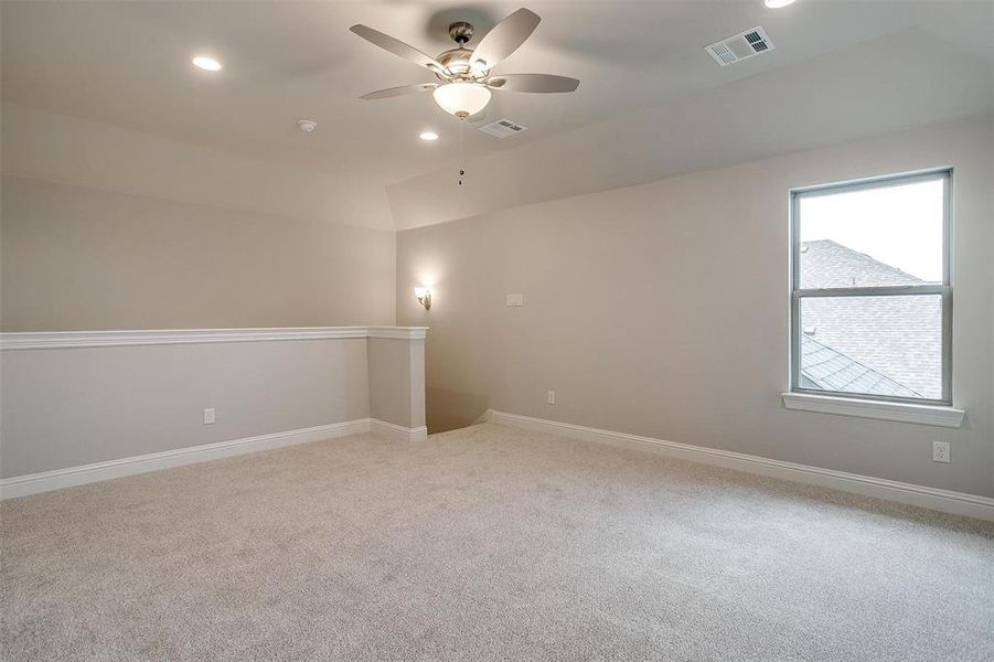 Empty room with light colored carpet and ceiling fan