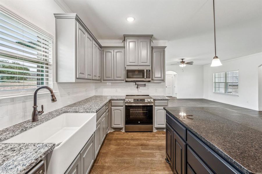 Kitchen featuring stainless steel appliances, backsplash, hardwood / wood-style floors, and gray cabinetry