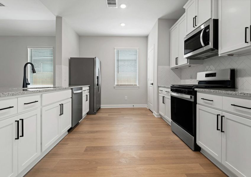Chef-ready kitchen with tile backsplash, granite countertops and white cabinets
