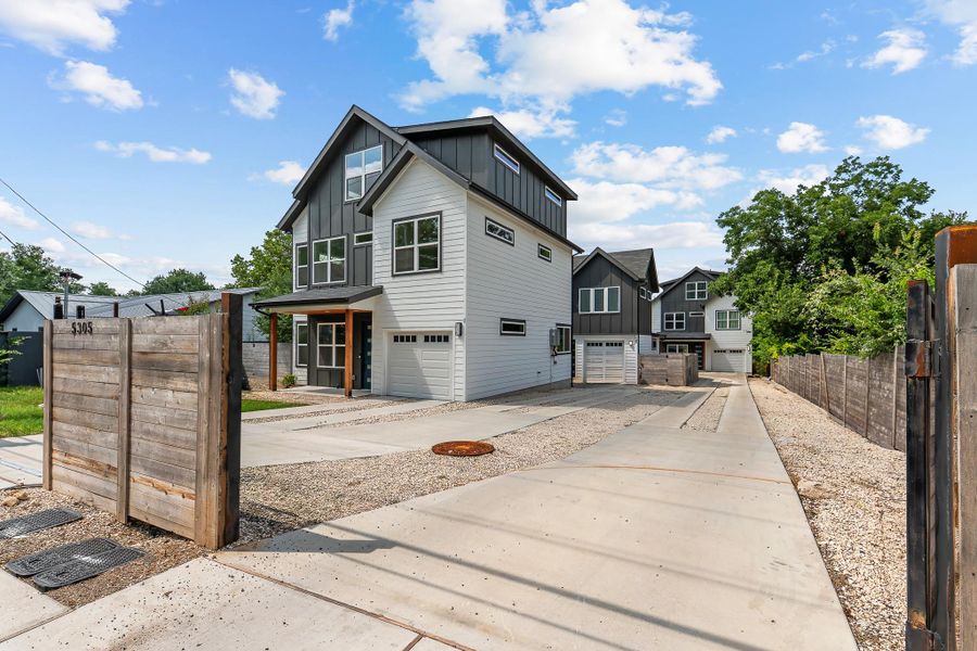 Modern townhomes line a concrete and gravel driveway, offering private garage access and contemporary curb appeal.