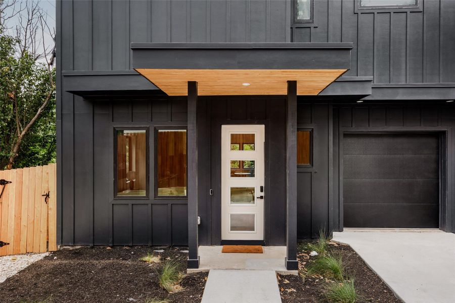 Doorway to property with board and batten siding, an attached garage, and driveway Doorway to property with board and batten siding, an attached garage, and driveway