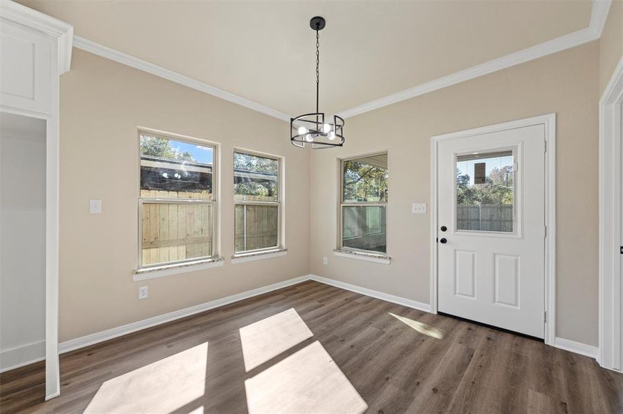 Unfurnished dining area with ornamental molding, a chandelier, and dark wood finished floors