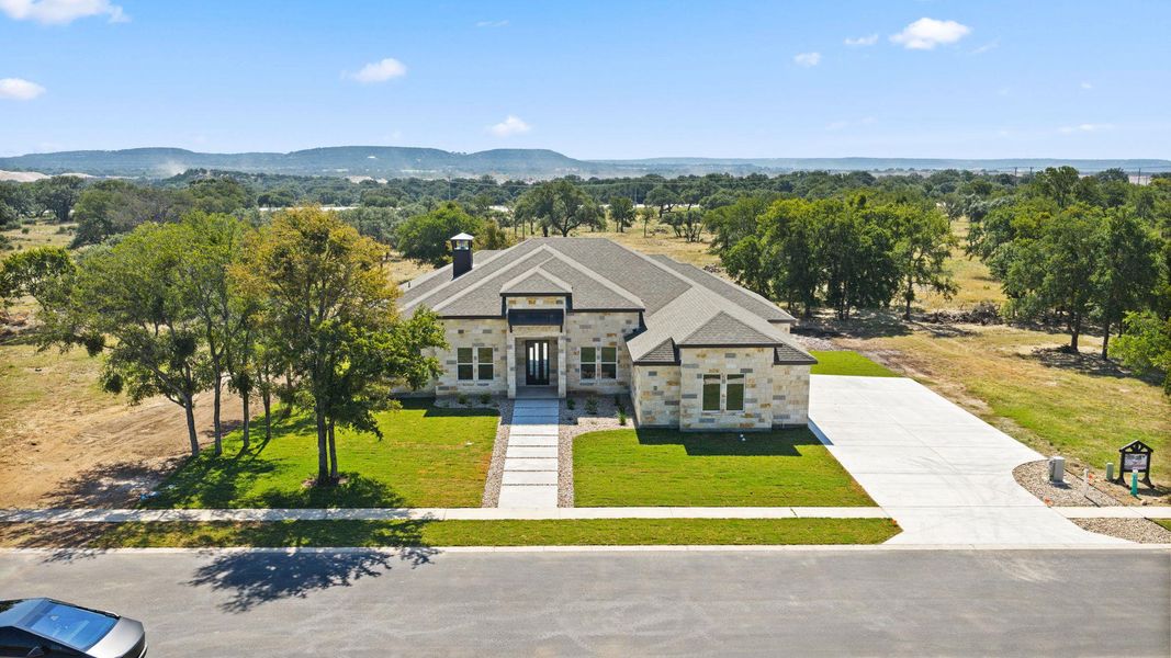 A refined stone facade home with an inviting walkway and extensive driveway set against a scenic, wooded backdrop. A refined stone facade home with an inviting walkway and extensive driveway set against a scenic, wooded backdrop.