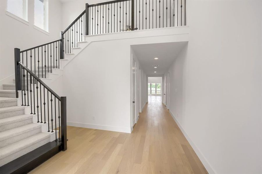 Two-story entryway with a carpeted staircase featuring black wrought iron balusters and wood newel posts
