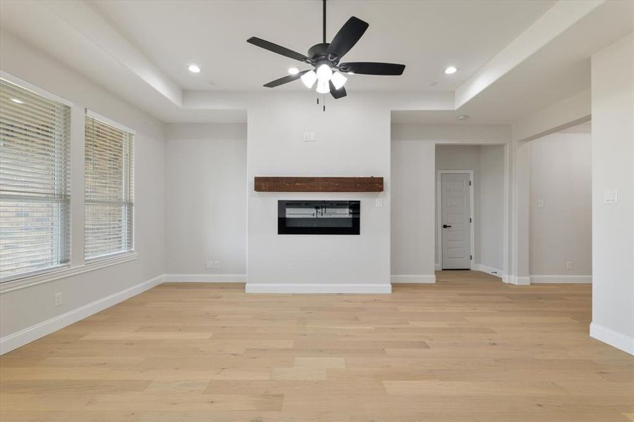 Unfurnished living room with a glass covered fireplace, light wood-style flooring, baseboards, and recessed lighting