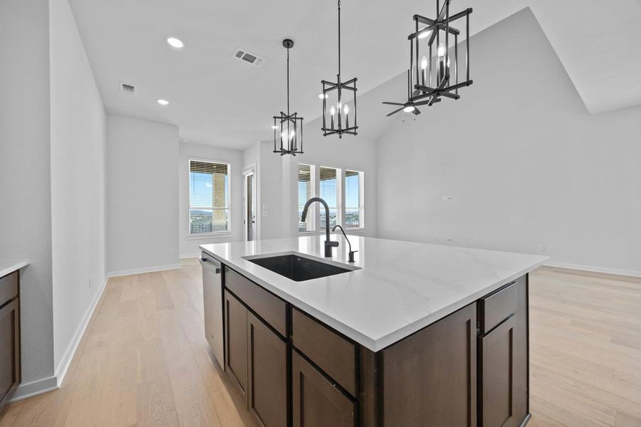 Kitchen with a chandelier, stainless steel dishwasher, light wood finished floors, dark brown cabinetry, and recessed lighting