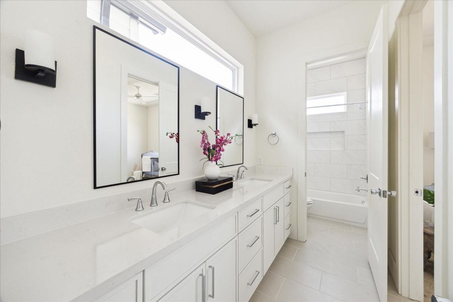 Well Organized - The Guest Bath features a double vanity with quartz countertop, under-mount sinks framed mirror flanked by a pair of wall sconces. Private toilet and bath.