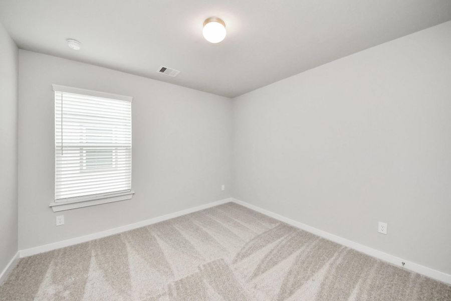Secondary bedroom features plush carpeting, large windows that let in plenty of natural light, bright paint, and spacious closets.