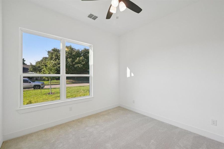 Empty room featuring light colored carpet and a ceiling fan
