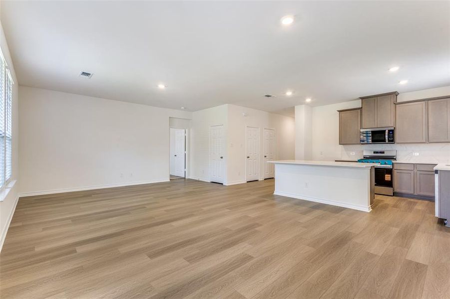 Kitchen with a kitchen island, stainless steel appliances, open floor plan, recessed lighting, and light wood-type flooring Kitchen with a kitchen island, stainless steel appliances, open floor plan, recessed lighting, and light wood-type flooring