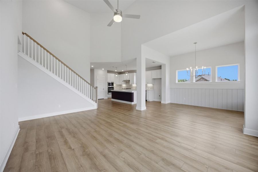An airy living space features soaring vaulted ceilings, natural light, and seamless flow into a modern kitchen.