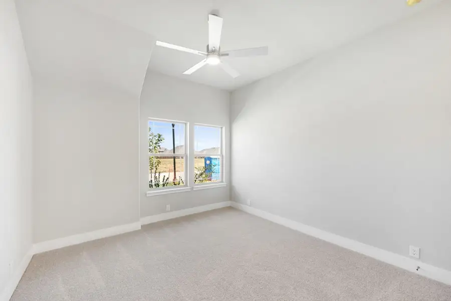 Empty bedroom with vaulted ceiling, ceiling fan, carpet flooring, and double windows