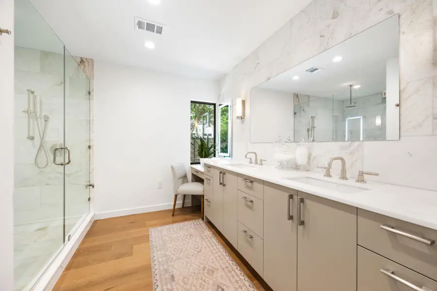 Full bath featuring a marble finish shower, double vanity, light wood finished floors, and recessed lighting