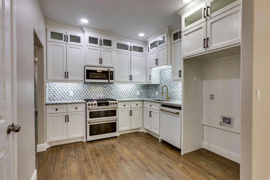 Kitchen with glass insert cabinets, white cabinets, dark wood-type flooring, and white appliances
