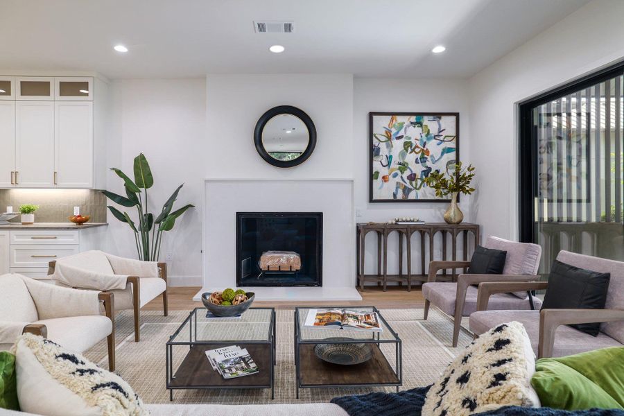 Living area featuring a white fireplace with a dark firebox and a contrasting round mirror