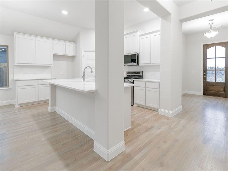 Kitchen with white cabinets, sink, stainless steel appliances, and light hardwood / wood-style flooring