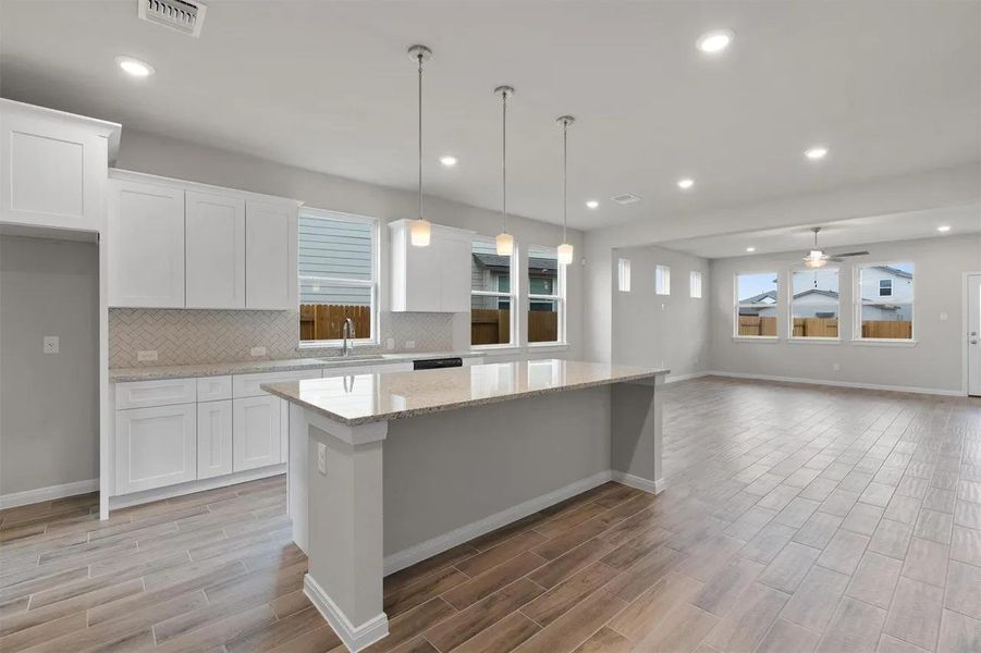 A well-lit kitchen with a spacious island flows seamlessly into a bright, open living area.