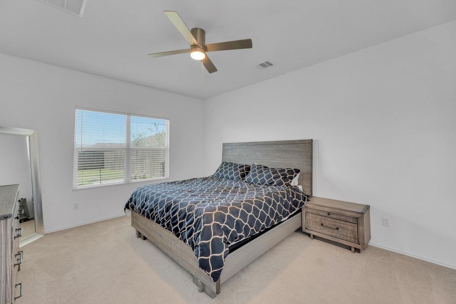 Bedroom with visible vents, light colored carpet, baseboards, and ceiling fan