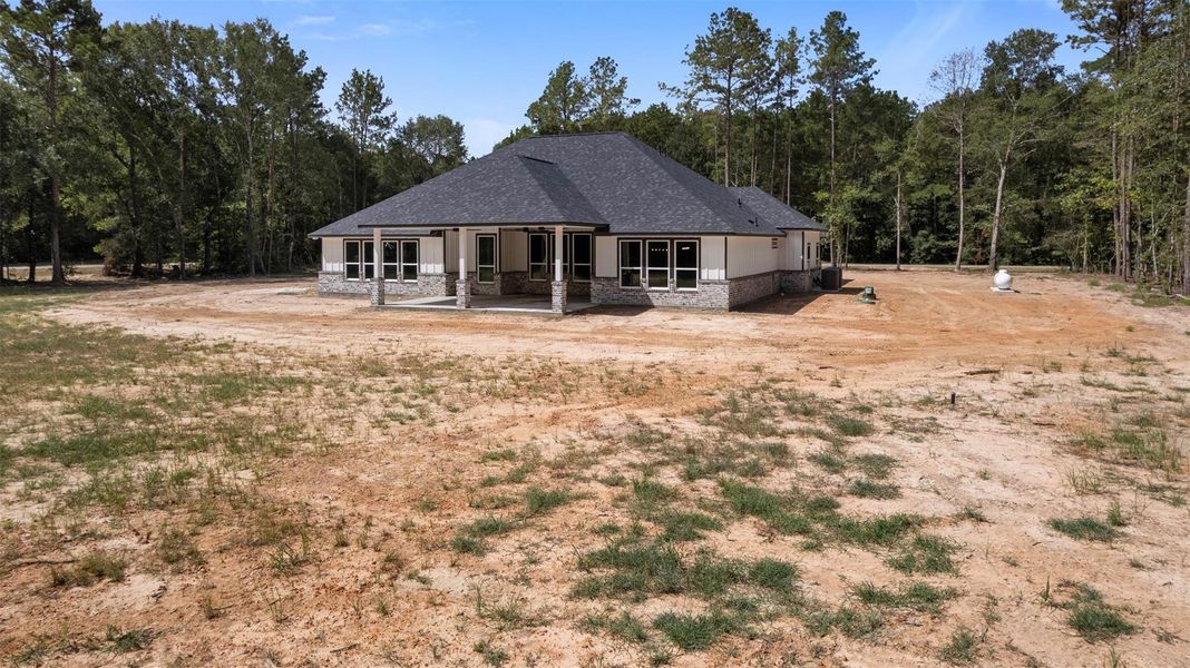 Charming single-story home with a spacious covered patio, nestled on a large, open lot surrounded by mature trees for added privacy.