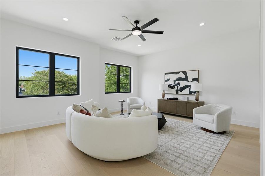 Spacious room featuring multiple large windows with black frames, recessed lighting, and a ceiling fan Spacious room featuring multiple large windows with black frames, recessed lighting, and a ceiling fan