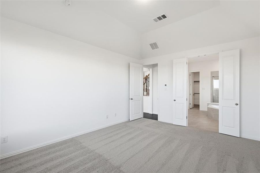 Spacious room featuring vaulted ceilings, light gray carpeting, and two sets of double doors