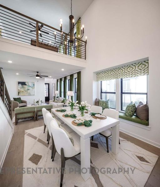 Dining room with wood finished floors, plenty of natural light, a chandelier, a high ceiling, and recessed lighting