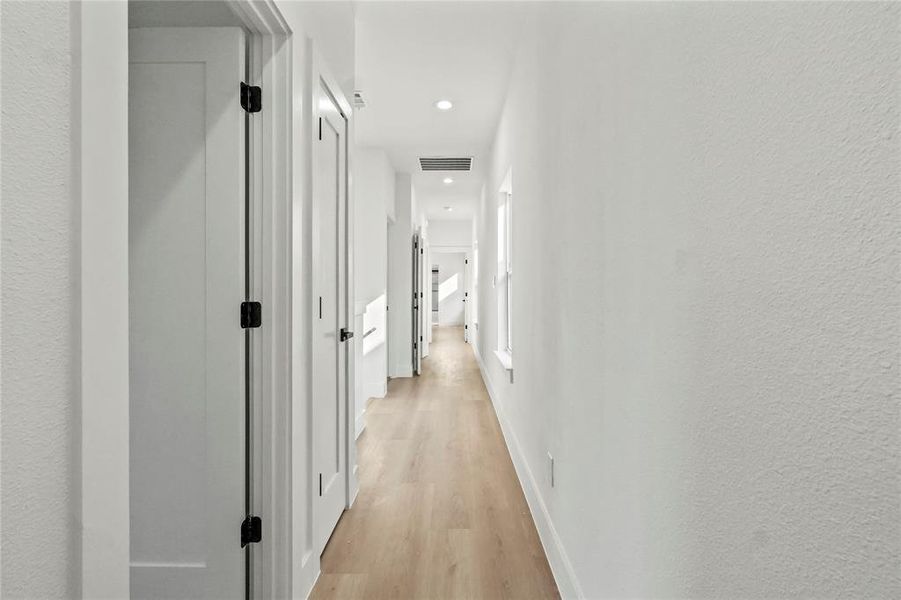 Corridor featuring light wood-style flooring, recessed lighting, and a textured wall Corridor featuring light wood-style flooring, recessed lighting, and a textured wall