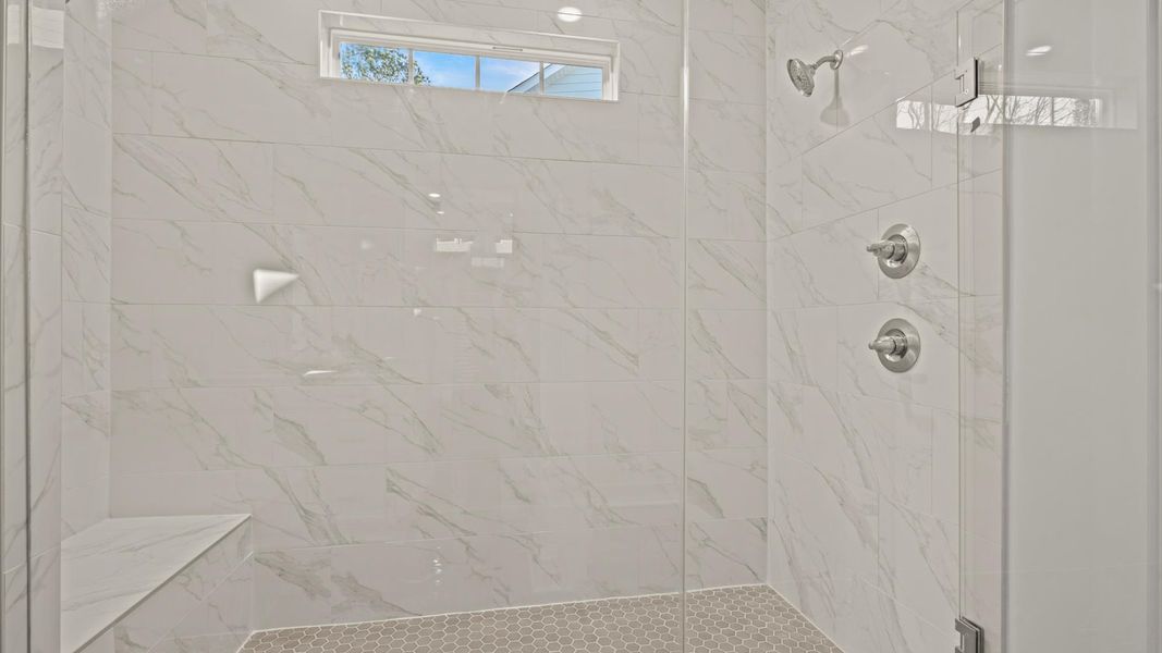 Elegant primary bathroom featuring a spacious tiled walk-in shower and dual vanity in this first-class DRB Homes design