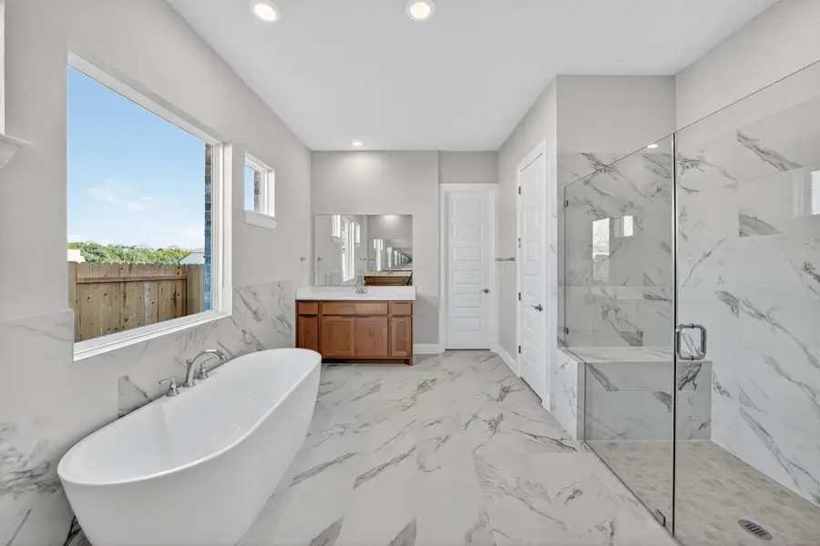 Full bath with vanity, a freestanding bath, a marble finish shower, recessed lighting, and light marble finish floors Full bath with vanity, a freestanding bath, a marble finish shower, recessed lighting, and light marble finish floors