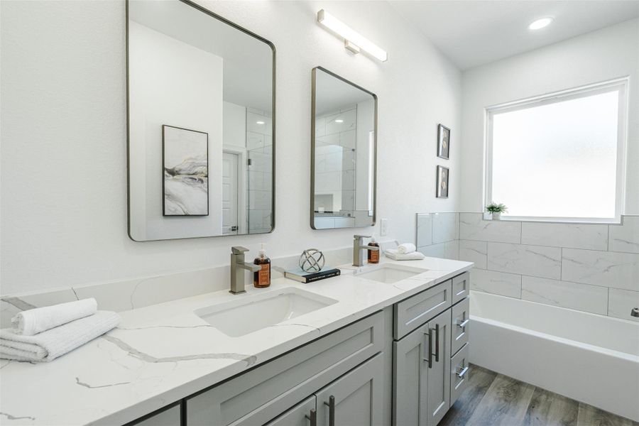Bathroom featuring double vanity, dark wood-type flooring, a bath, and a shower