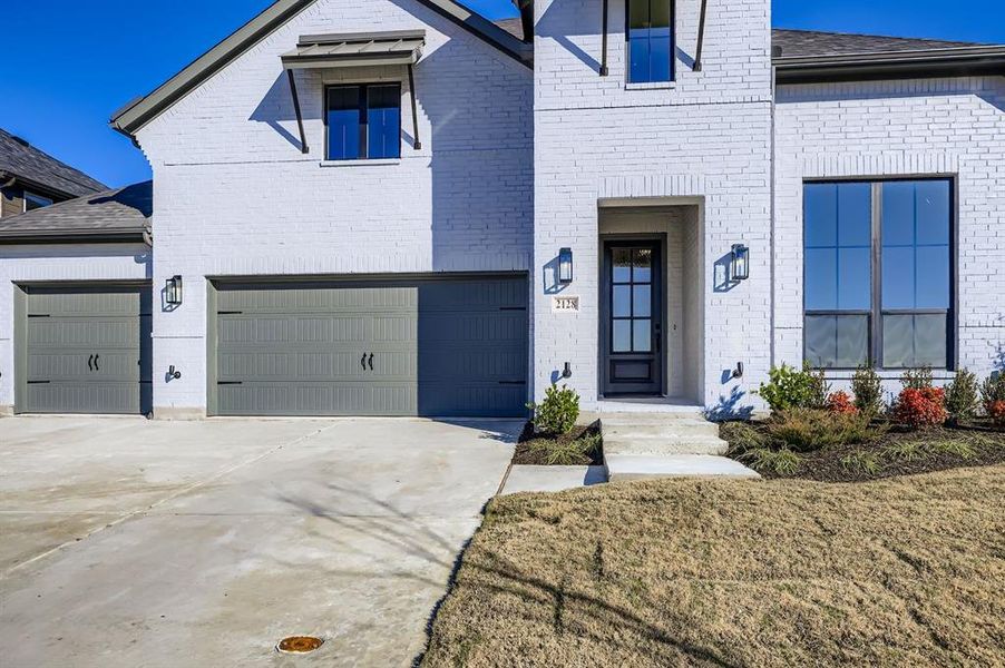 French provincial home featuring brick siding, driveway, and a front lawn