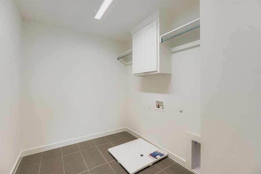 Washroom with cabinet space, washer hookup, dark tile patterned flooring, and hookup for a gas dryer
