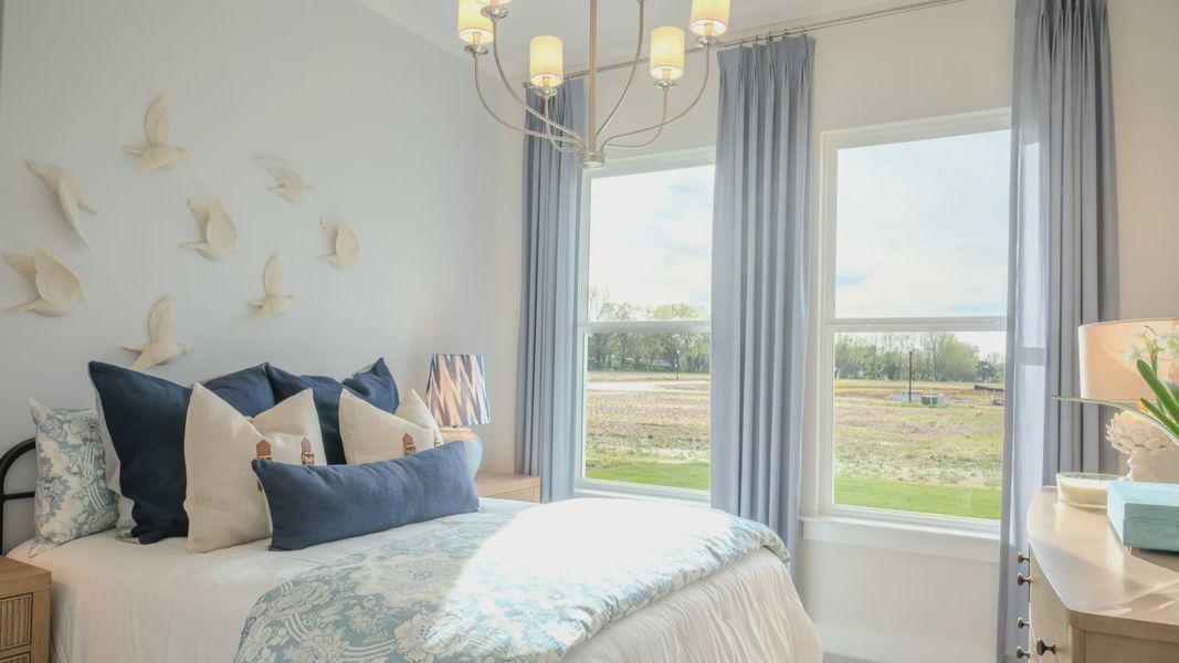 Secondary bedroom with two windows, curtains, and cozy bed