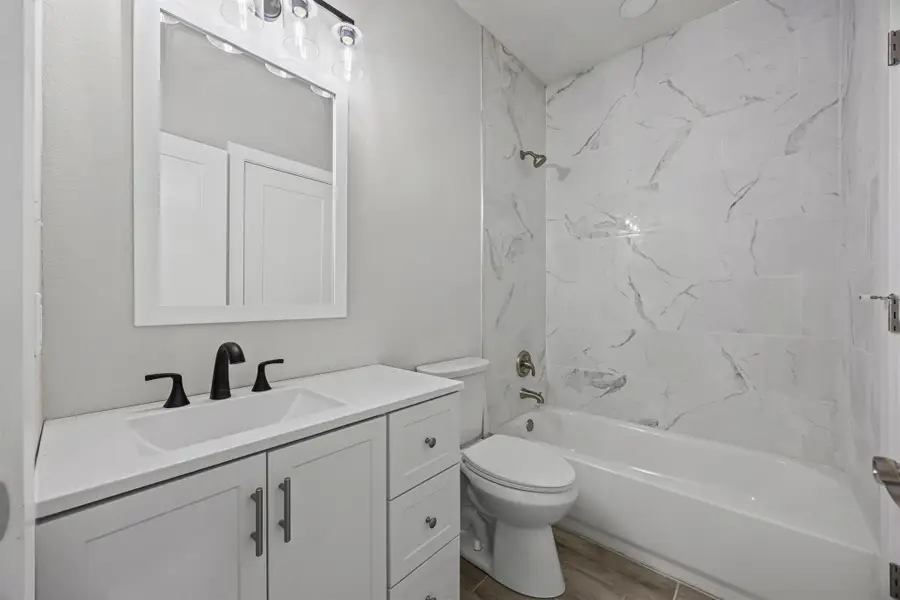 Full bathroom featuring shower / washtub combination, vanity, and wood finished floors Full bathroom featuring shower / washtub combination, vanity, and wood finished floors