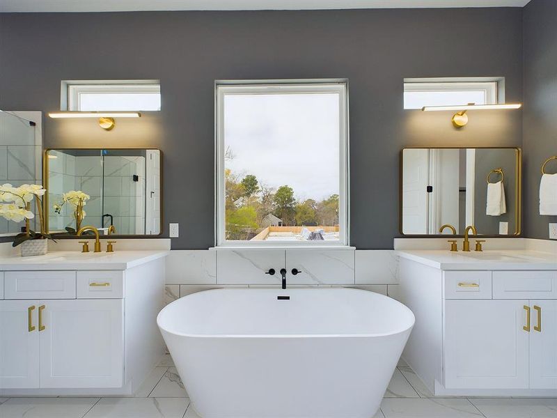 Convenience and luxury continues to be displayed in the dual vanities that this primary bathroom offers. Quartz countertops accentuated by the rich allure of bronze hardware, come together seamlessly to complement the overhead lighting thoughtfully selected for this space. *All interior photos are from the model home: 9007 Orange Springs Dr.*