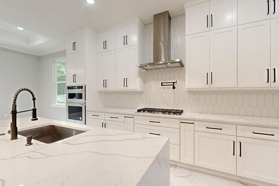 Kitchen with quartz counters, backsplash, white cabinets, and recessed lighting Kitchen with quartz counters, backsplash, white cabinets, and recessed lighting