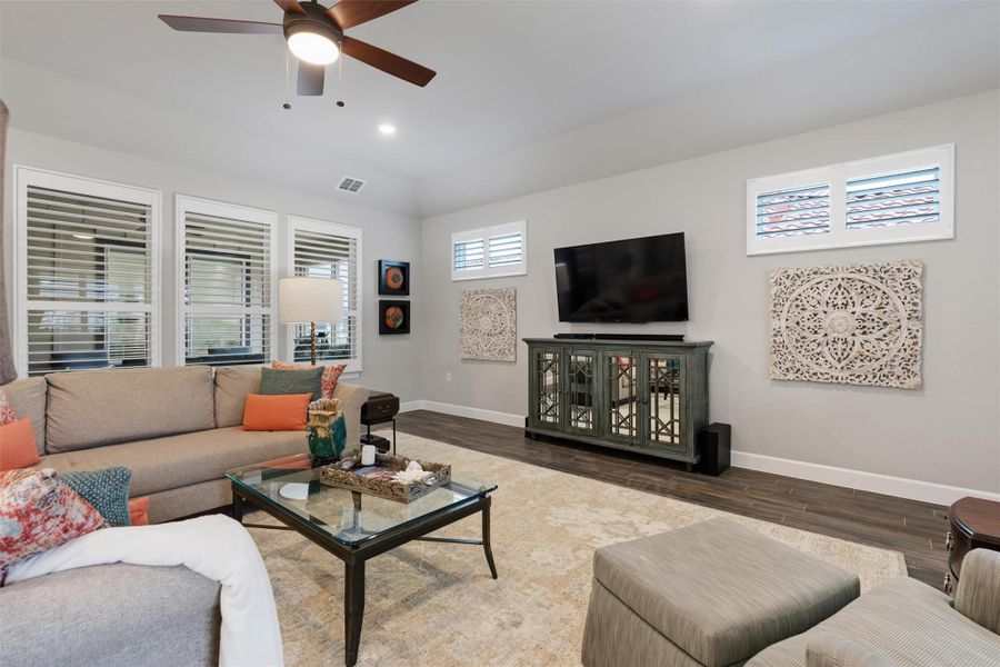 This view of the family room shows the windows overlooking the interior courtyard/patio and the upper windows on the tv wall. Wood-look tile runs through the home and is a light neutral color This view of the family room shows the windows overlooking the interior courtyard/patio and the upper windows on the tv wall. Wood-look tile runs through the home and is a light neutral color