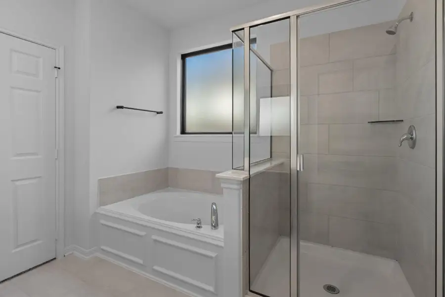 This additional view of your primary bathroom features tile flooring, fresh paint, walk-in shower, a separate garden tub, and a large walk-in closet.
