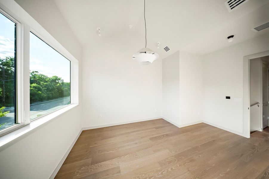 Unfurnished room with wood finished floors, vaulted ceiling, and baseboards