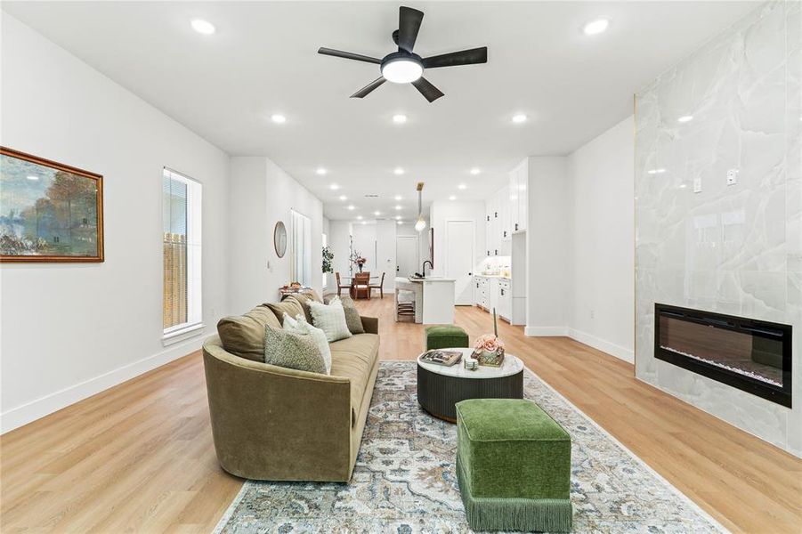 Living area with a fireplace, recessed lighting, a ceiling fan, and light wood finished floors Living area with a fireplace, recessed lighting, a ceiling fan, and light wood finished floors
