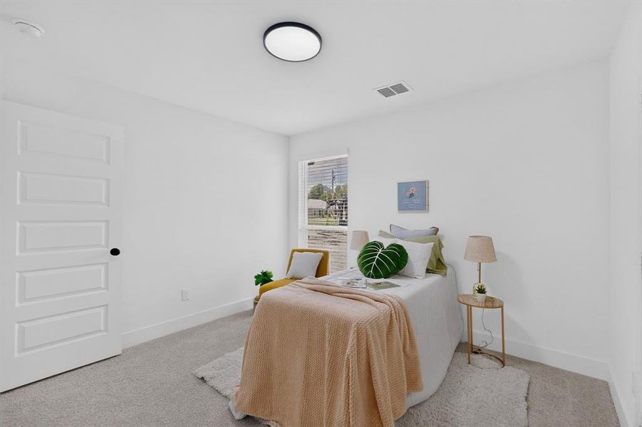 Light-filled bedroom featuring plush gray carpeting, white five-panel interior door with black hardware, and a modern flush-mount ceiling light