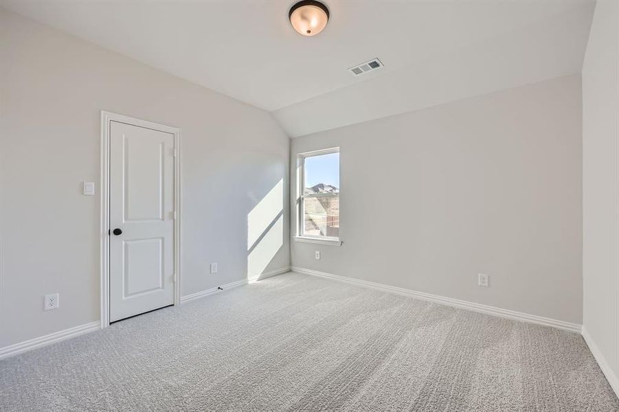 Carpeted empty room with vaulted ceiling